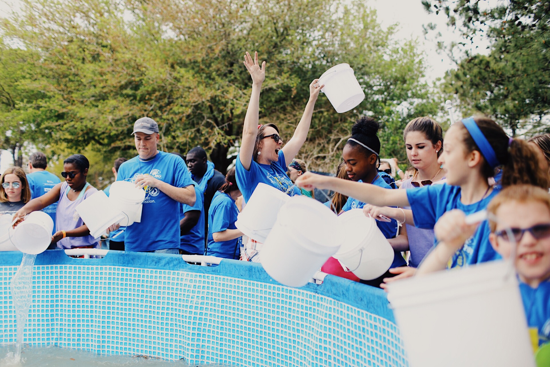 A walker celebrates at the end of Water Mission's Walk for Water as she dumps her bucket into the pool.