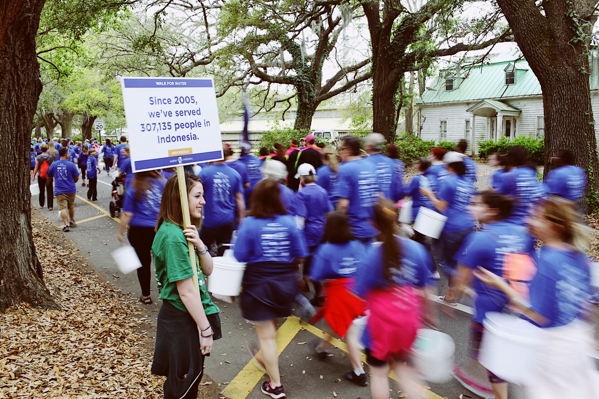 A volunteer holds a fact sign along Water Mission's Walk for Water route.