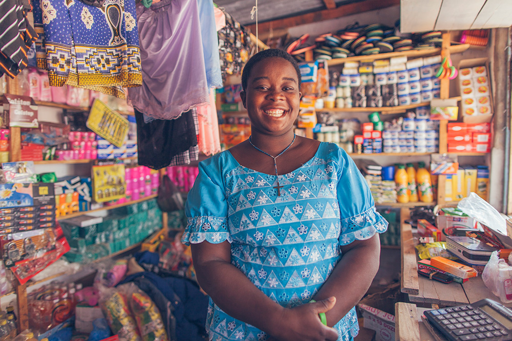 A woman smiles as she proudly stands in her shop.