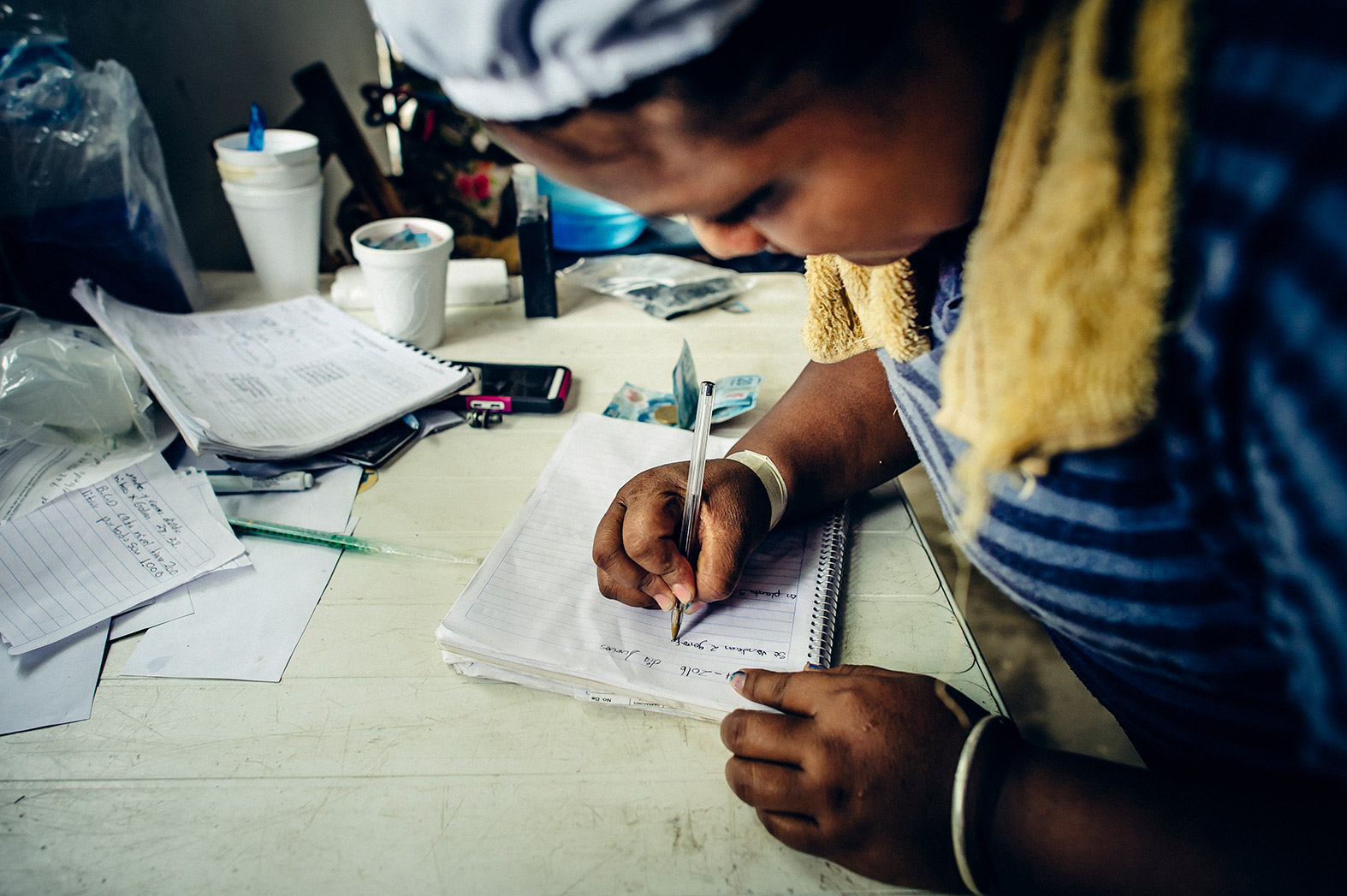 A woman records payments made for safe water.