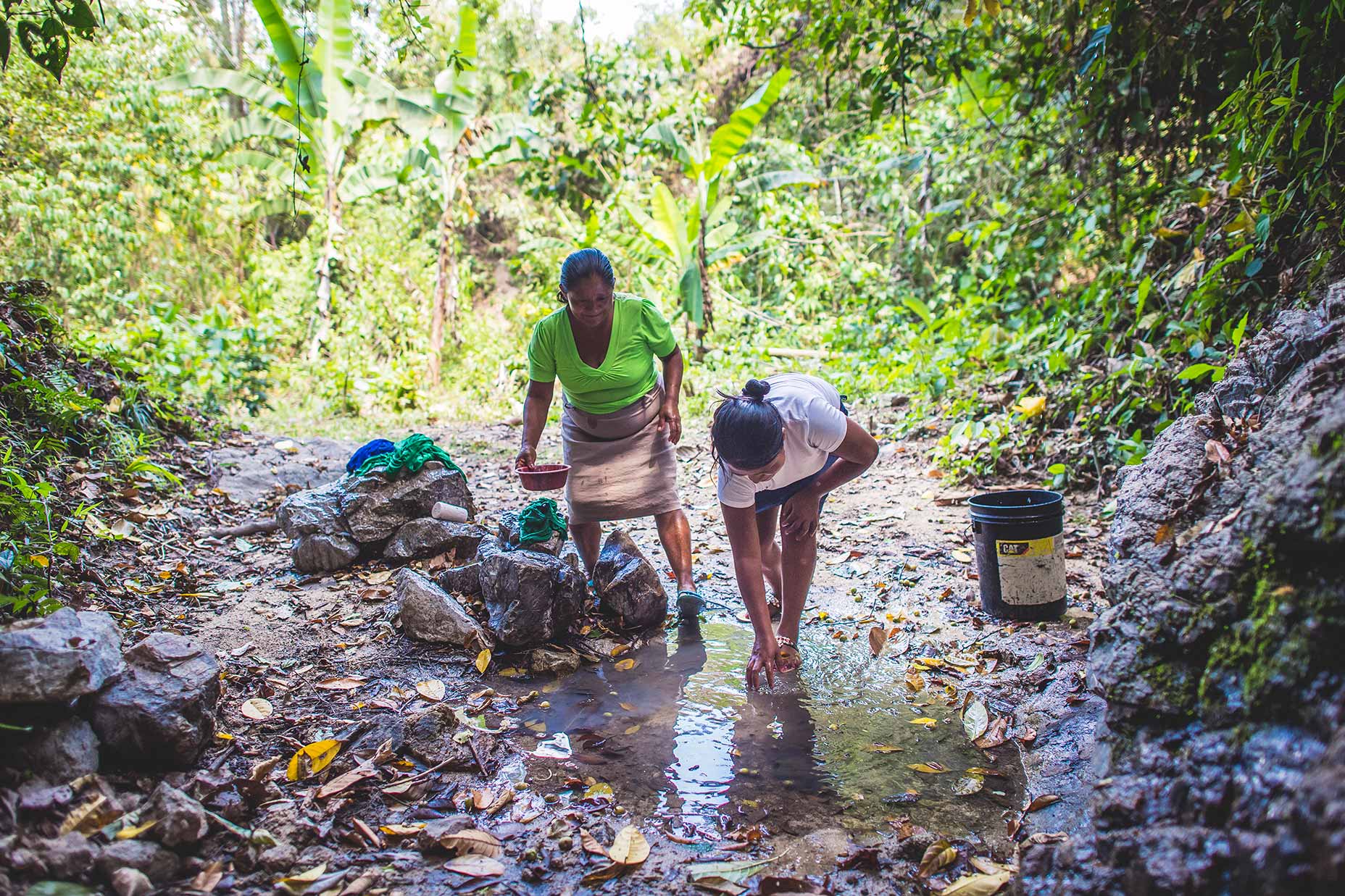 Honduras women wash clothes in the small water source near their house.