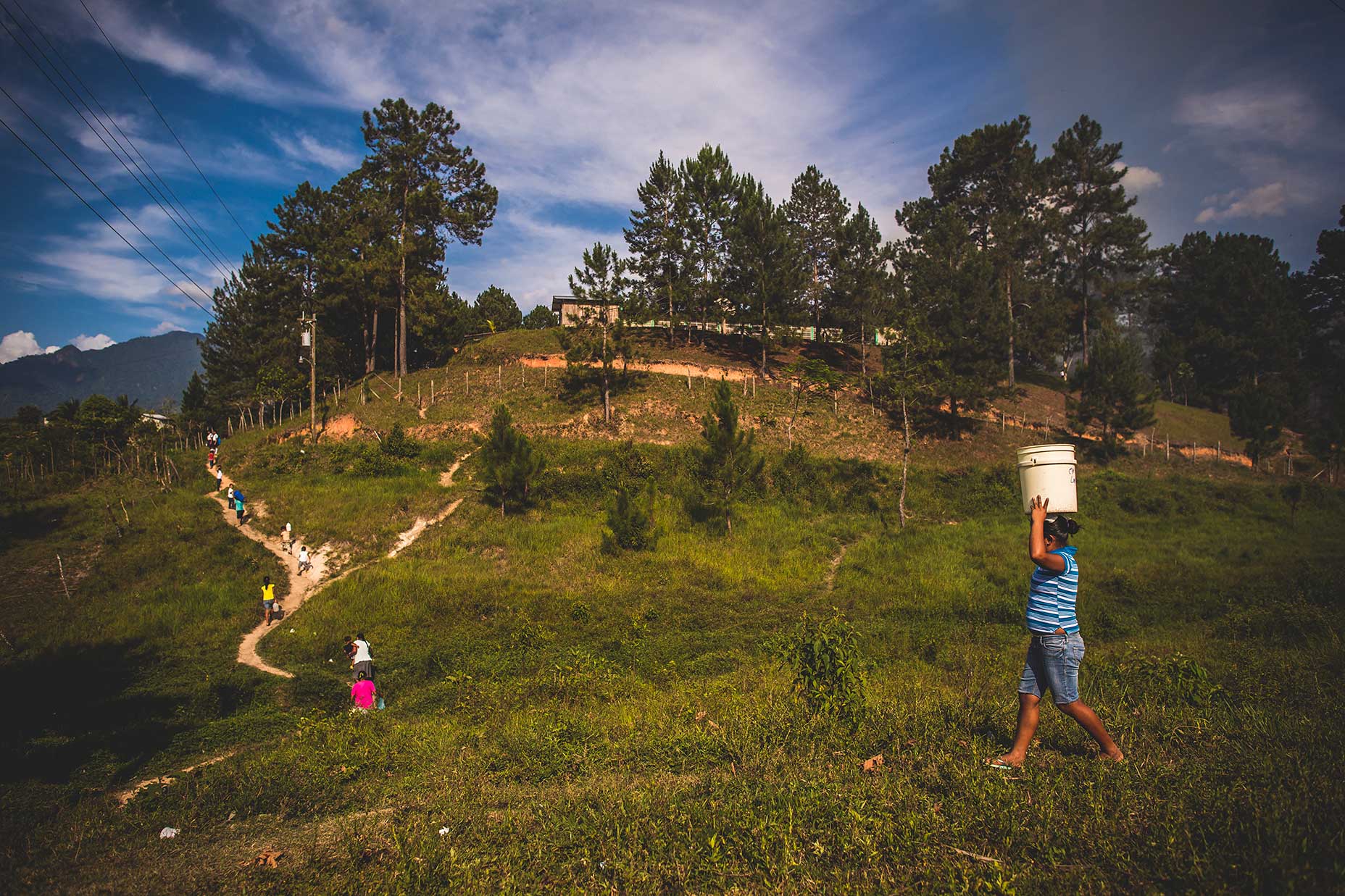 Women walk in Honduras to collect water.