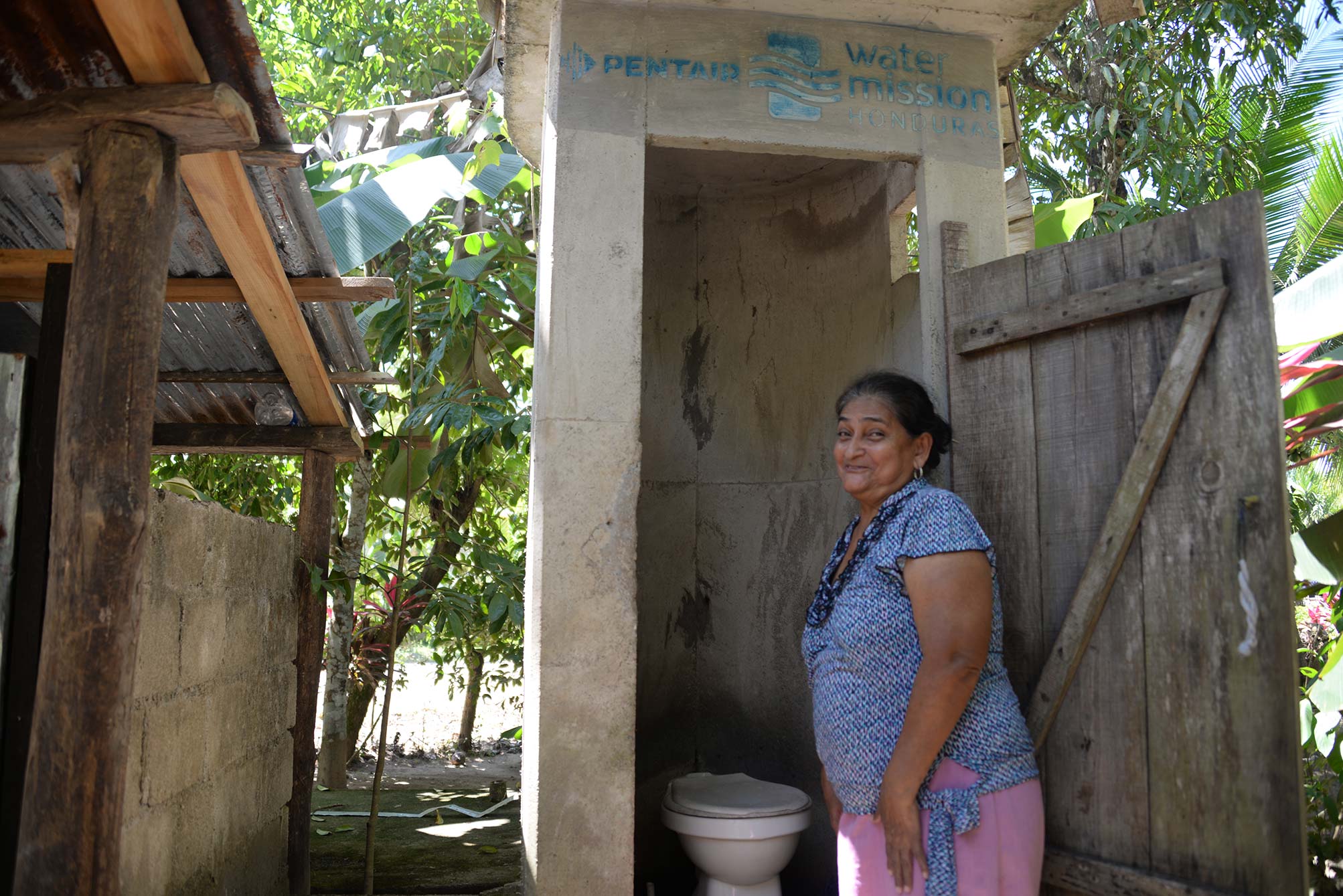 A woman in Honduras enjoys her latrine installed by Water Mission and Pentair.