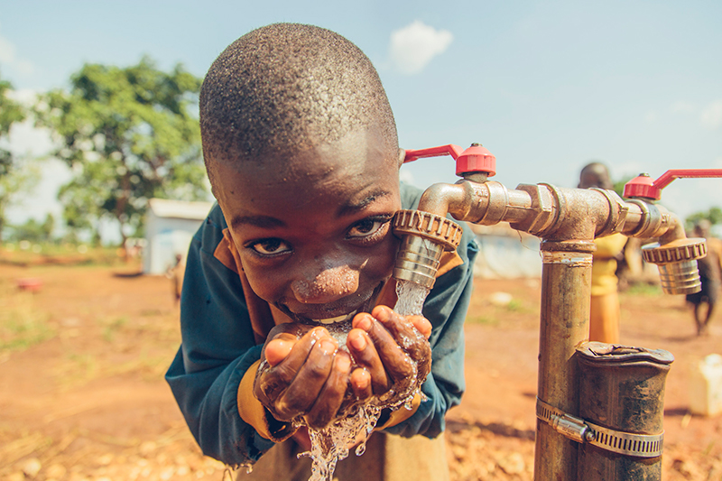 A young boy drinks safe water produced by the largest solar powered safe water treatment system.