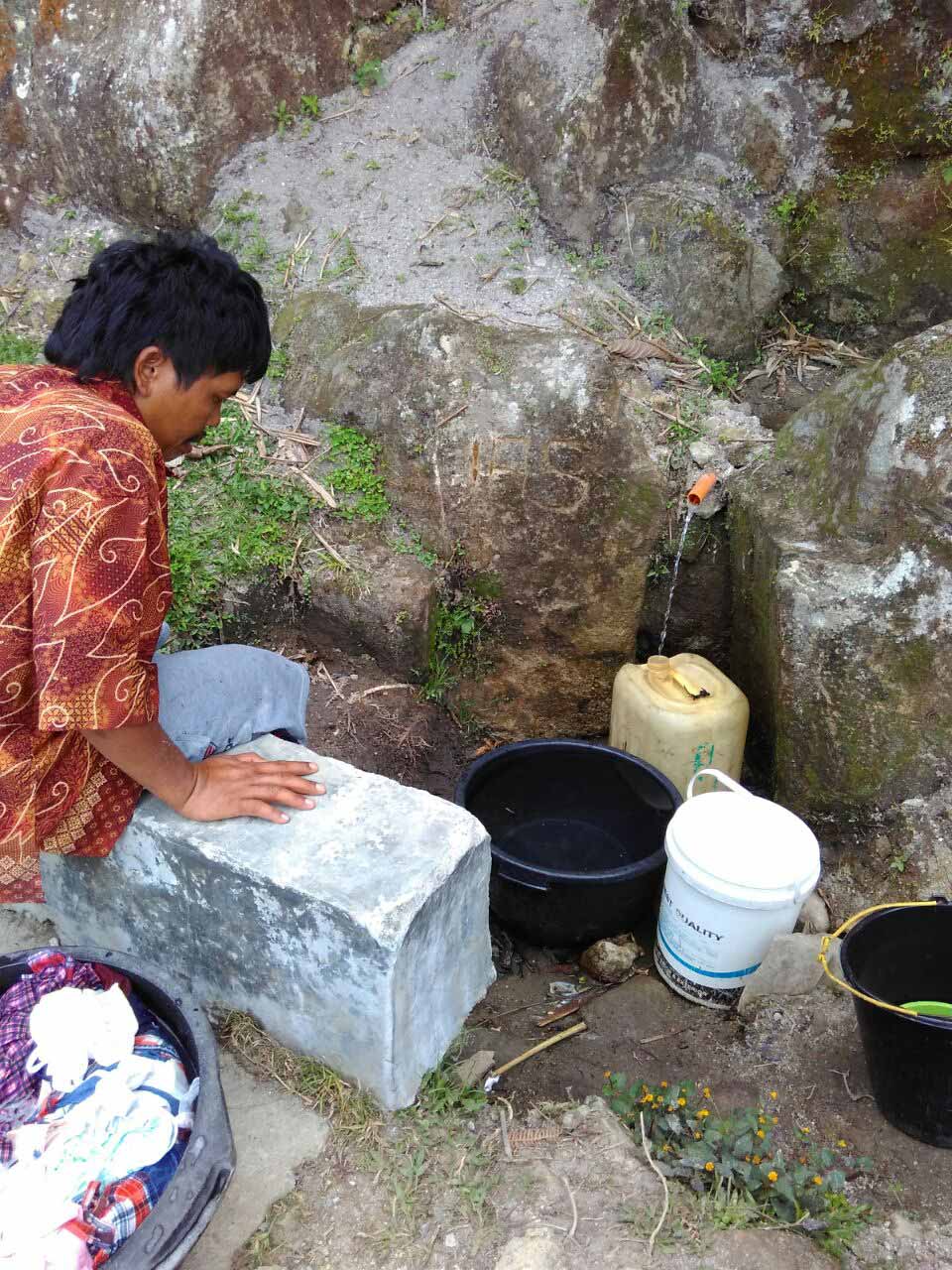A community member gathers dirty water in Huta Ginjang, Indonesia.