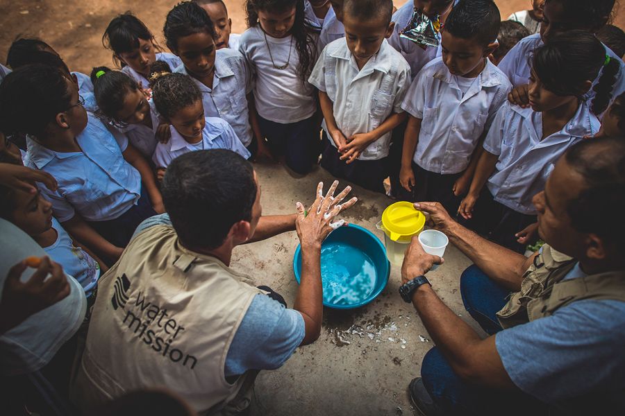 A community WASH promoter teaches students how to wash their hands.