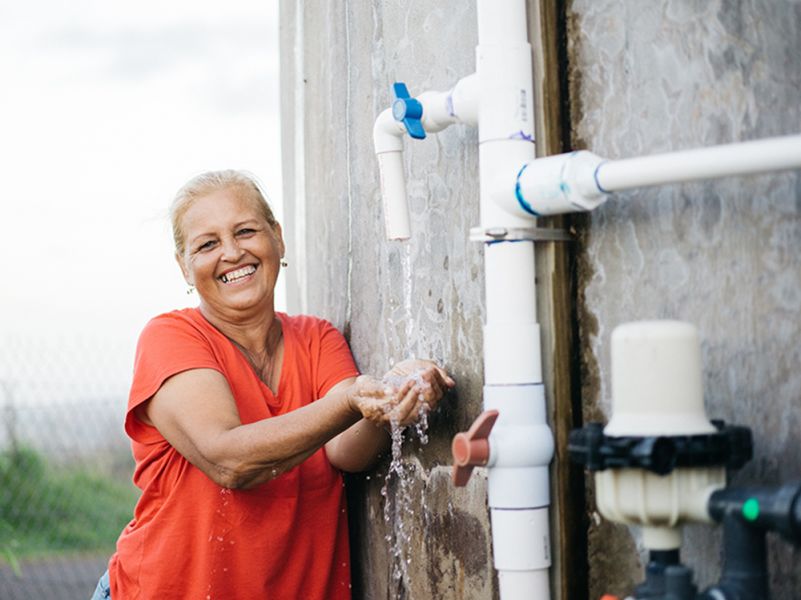 A woman smiles after safe water is restored to her community.