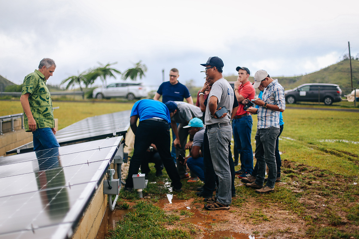 Water Mission, Grundfos, and Blue Planet Energy staff with a solar array.
