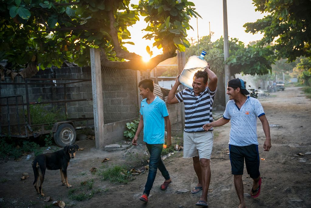 Raul and his sons carry safe water to the restaurant.