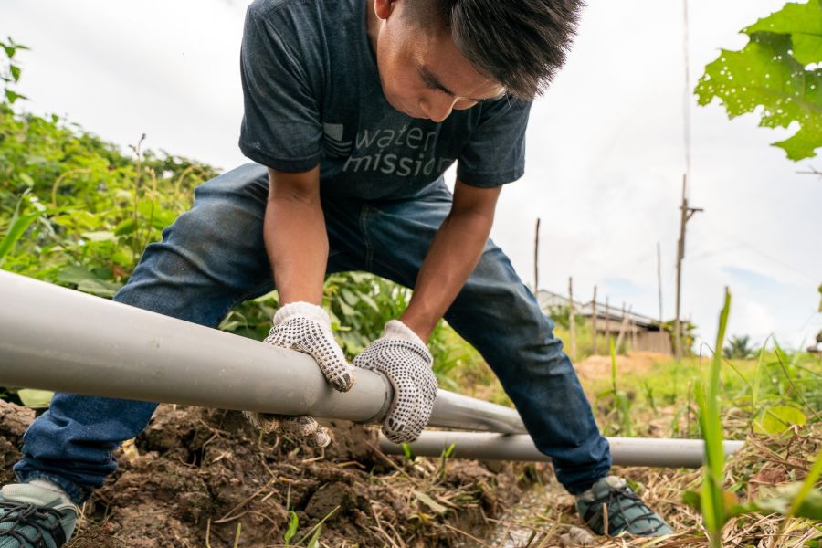 A worker installs pipe for a safe water treatment system. 