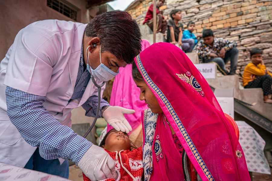 A mother holds her sick child as a doctor check's the child's vital signs. 