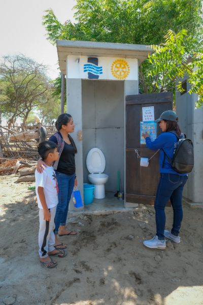 a woman shows a mother and child a Water Mission Healthy Latrine. 